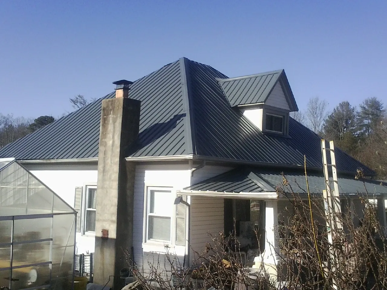 Dark blue standing seam metal roof on a white farmhouse with dormer — Slate & Tile Roof Repair by Roofing Brothers in San Juan Bautista