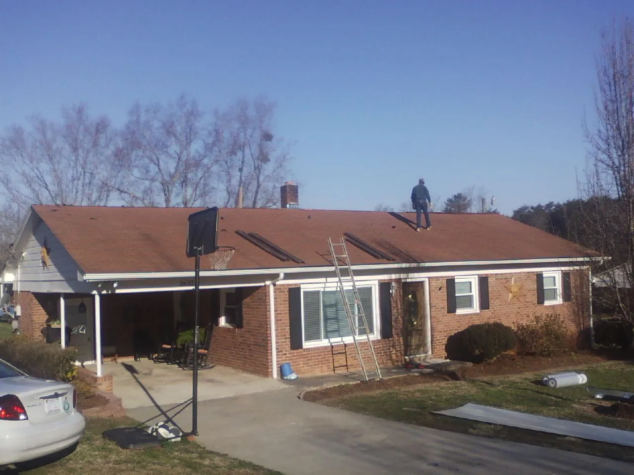 Roofer stripping a shingle roof on a brick ranch before metal panels in San Juan Bautista