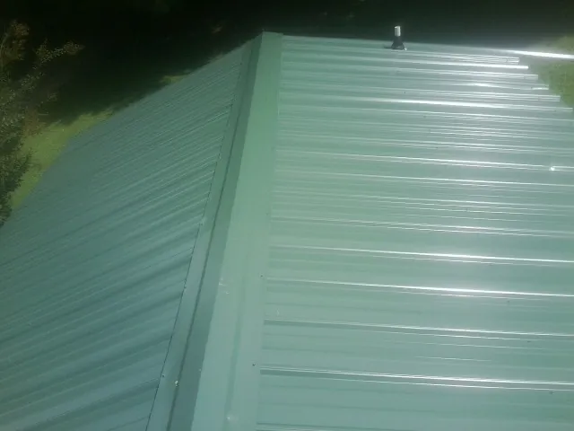 New green metal panels meeting at the ridge of a roof — Flat Roof Repair work by our crew in San Juan Bautista