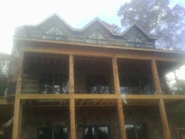 Dormers and porch framing on a large log home under construction — Roof Coating work by our crew in San Juan Bautista