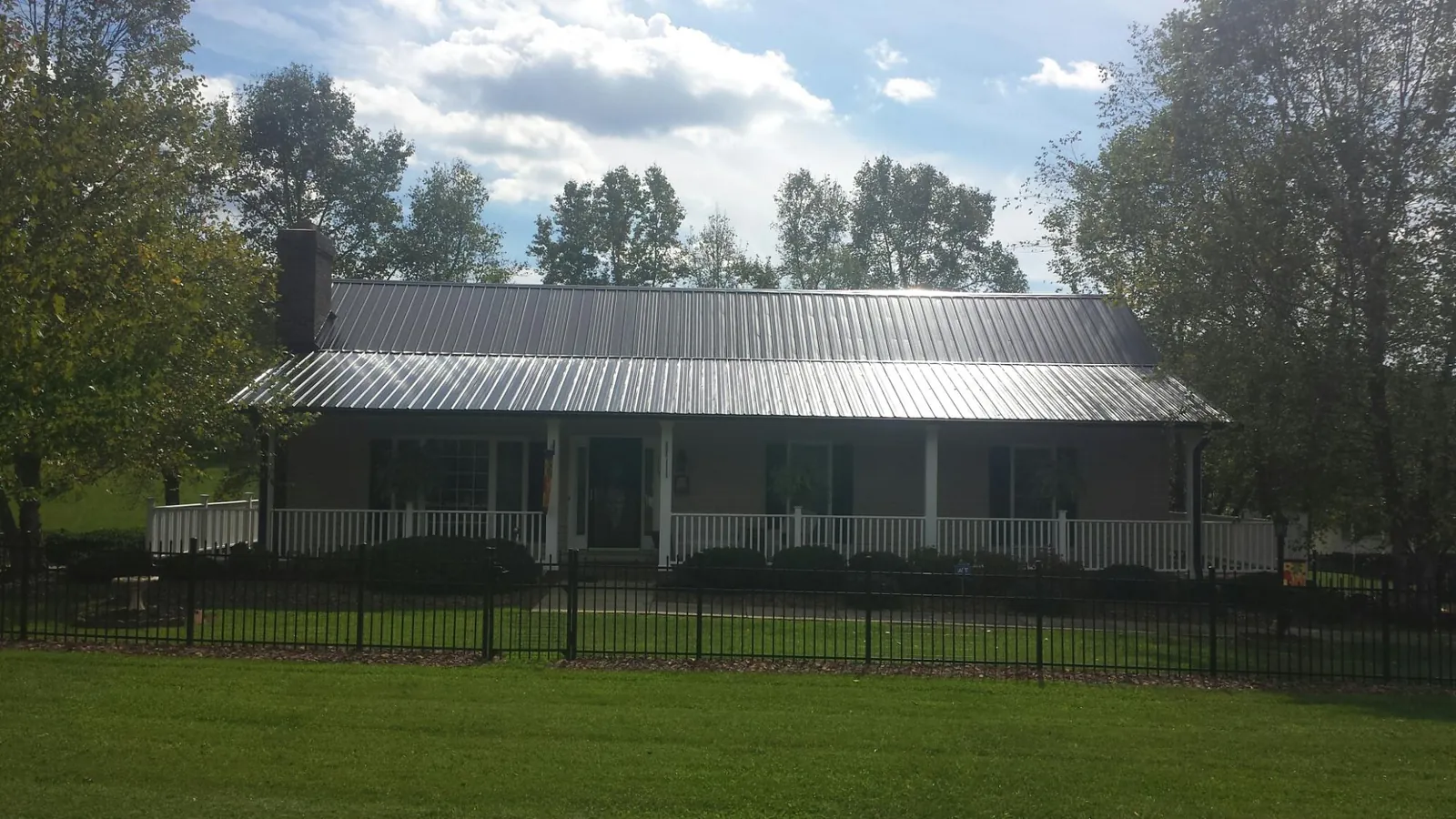 Gray metal roof on a brick ranch with a full width front porch — Gutter Guard Installation work by our crew in San Juan Bautista