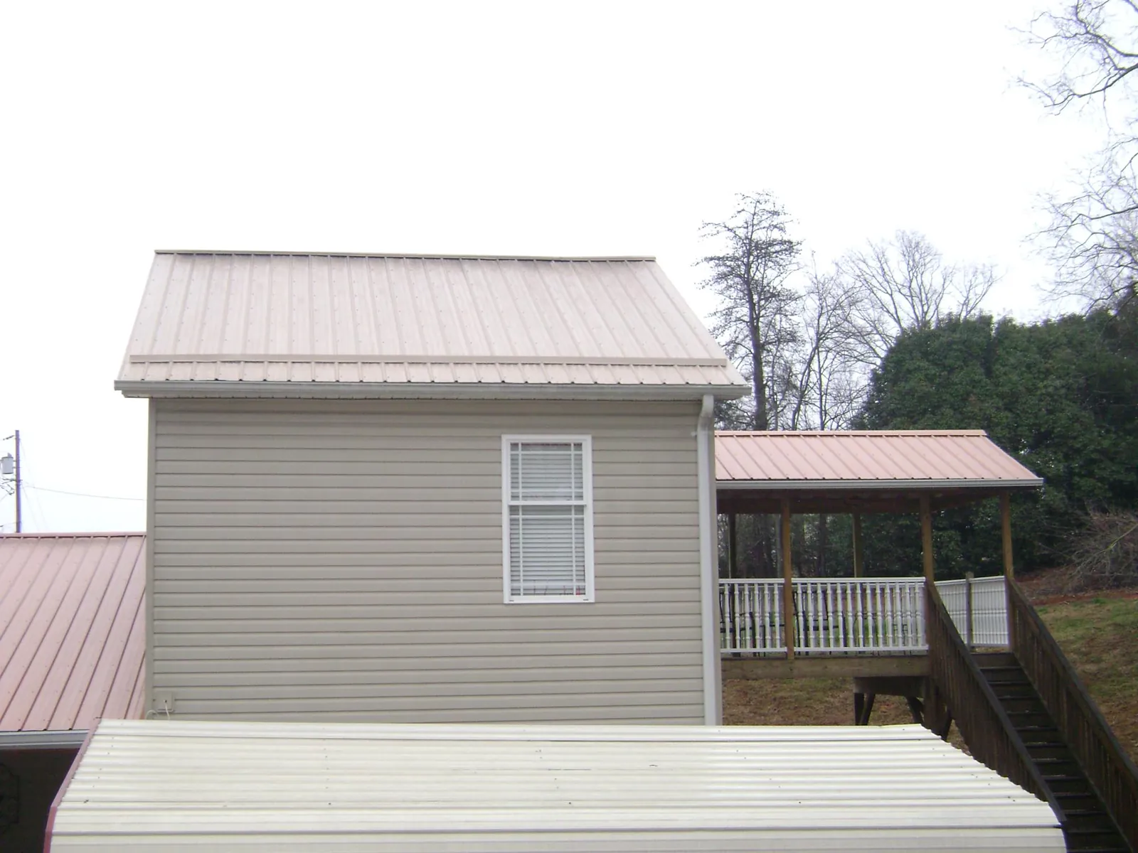 Tan metal roofs on a two story addition and attached porch, from a Roof Replacement job in San Juan Bautista