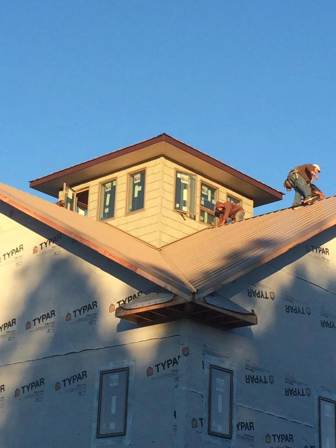 Roofers working around a rooftop cupola on a new metal roof at sunset — Roof Waterproofing in San Juan Bautista by Roofing Brothers